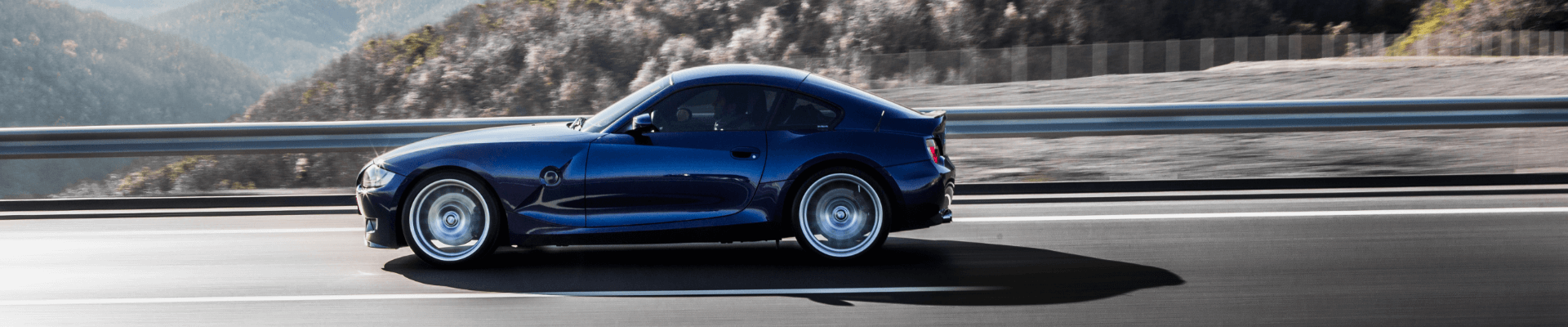 navy-blue-coupe-sedan-driving-highway-accross-mountains