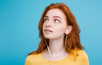people-entertainment-hobby-concept-cheerful-young-african-american-woman-with-curly-hair-holds-modern-smartphone-listens-music-via-stereo-headphones-poses-against-vivid-orange-background-3