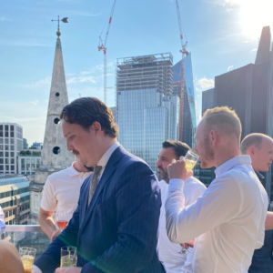 A group of people in a crowded rooftop bar at AdTonos' July 'AudioSushi' Event